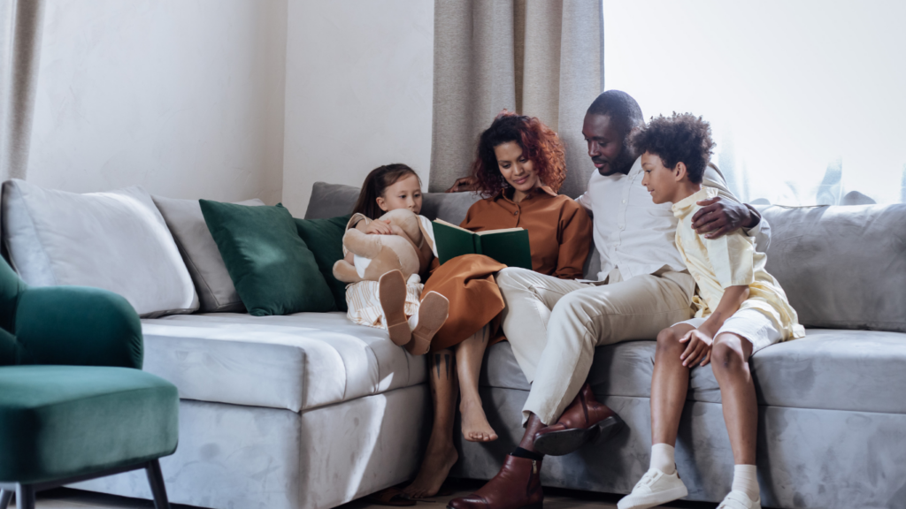 A family sitting on a couch reading a book