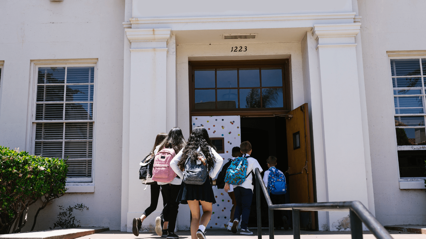 a group of children running down the steps of a school