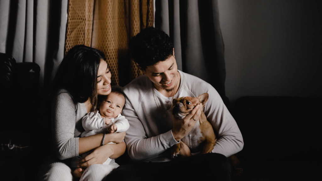 A person sitting on a couch with a baby and a dog