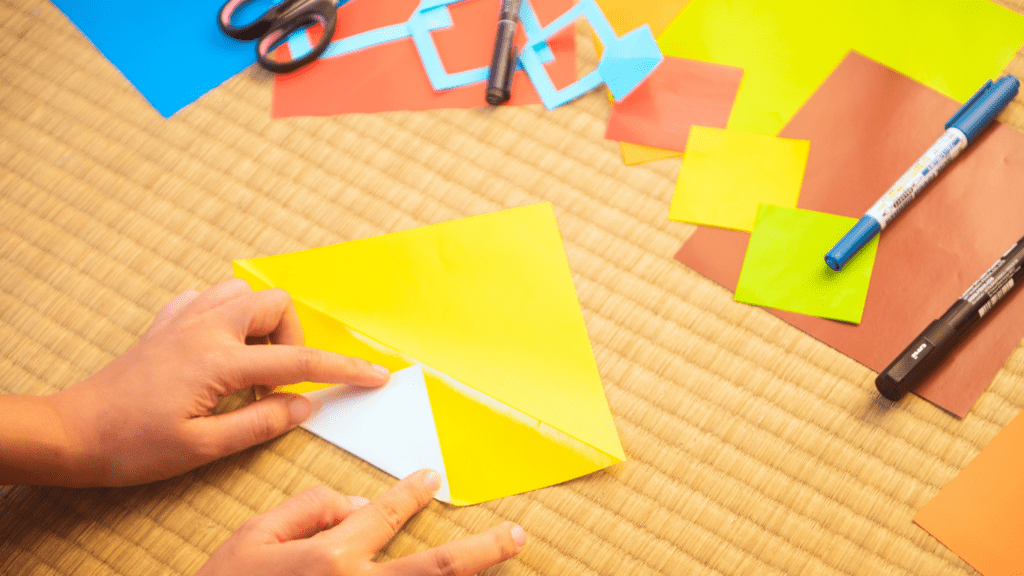 A person making a paper kite with scissors and glue