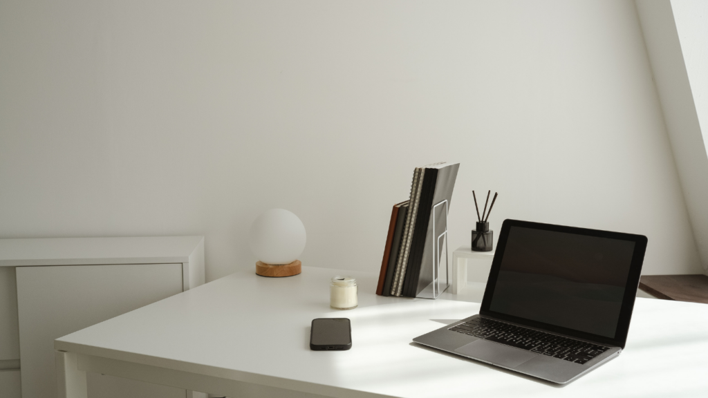 a desk with a laptop and chair in front of a window