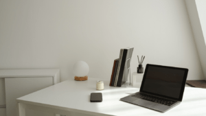 a desk with a laptop and chair in front of a window