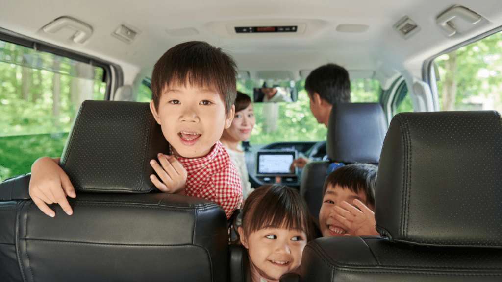 A family sitting in the back seat of a car