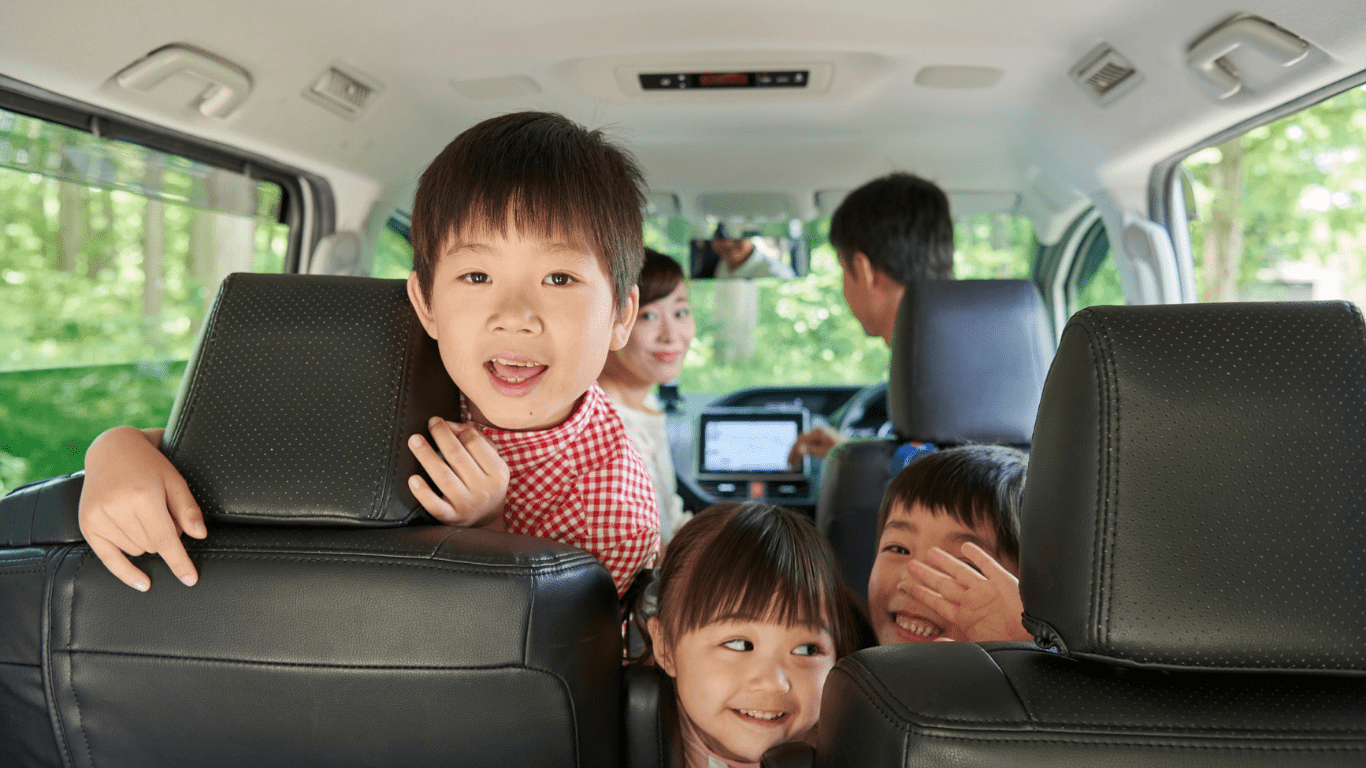 A family sitting in the back seat of a car