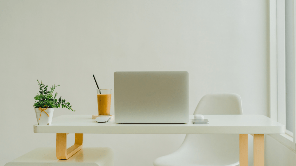 a desk with a laptop and chair in front of a window