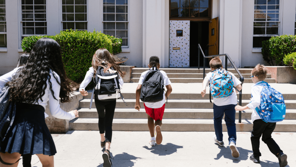 a group of children running down the steps of a school