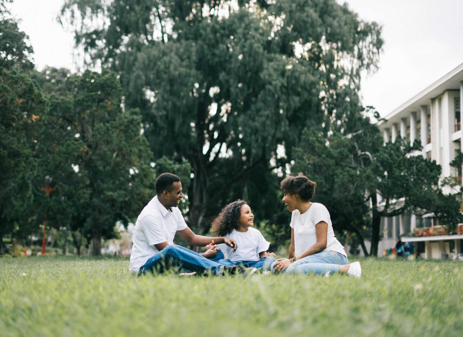 A happy black family enjoying quality time together outdoors in a lush green park.