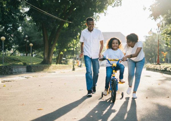 pexels-photo-1128318-1128318 Happy family teaching their child to cycle on a sunny day outdoors.